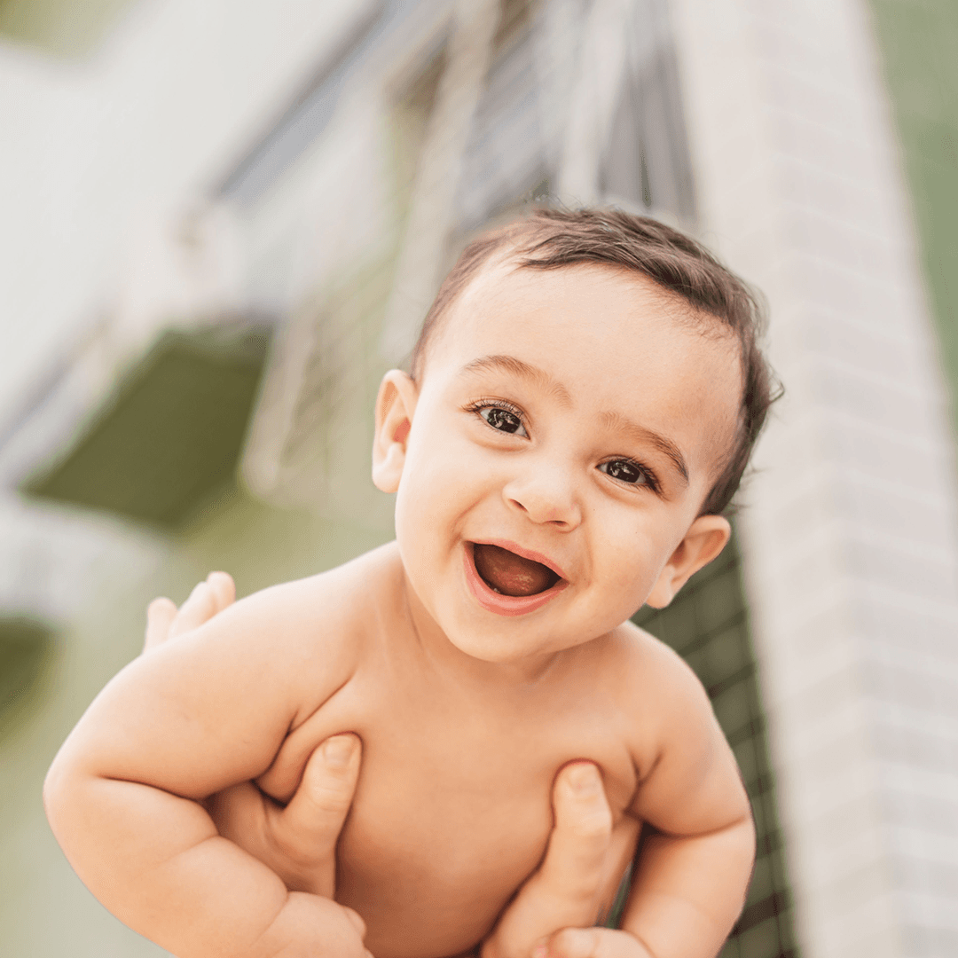 Close-up of a smiling baby held up outdoors