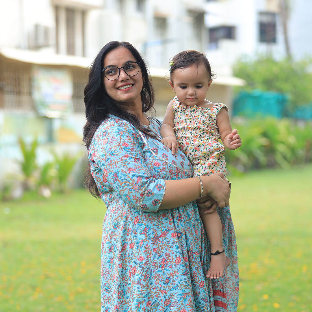 Mother smiling while holding her baby outdoors